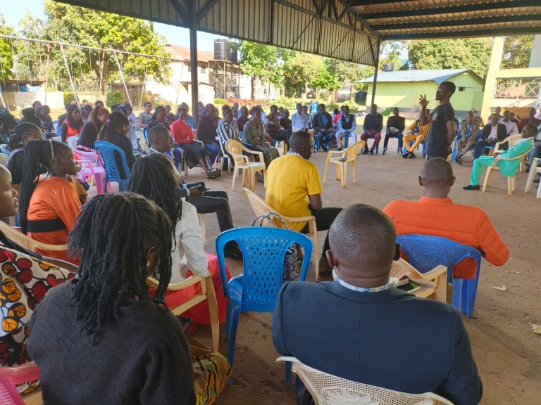 Members seated in fellowship under a shelter