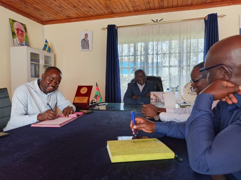 Men seated at a desk signing documents in an office